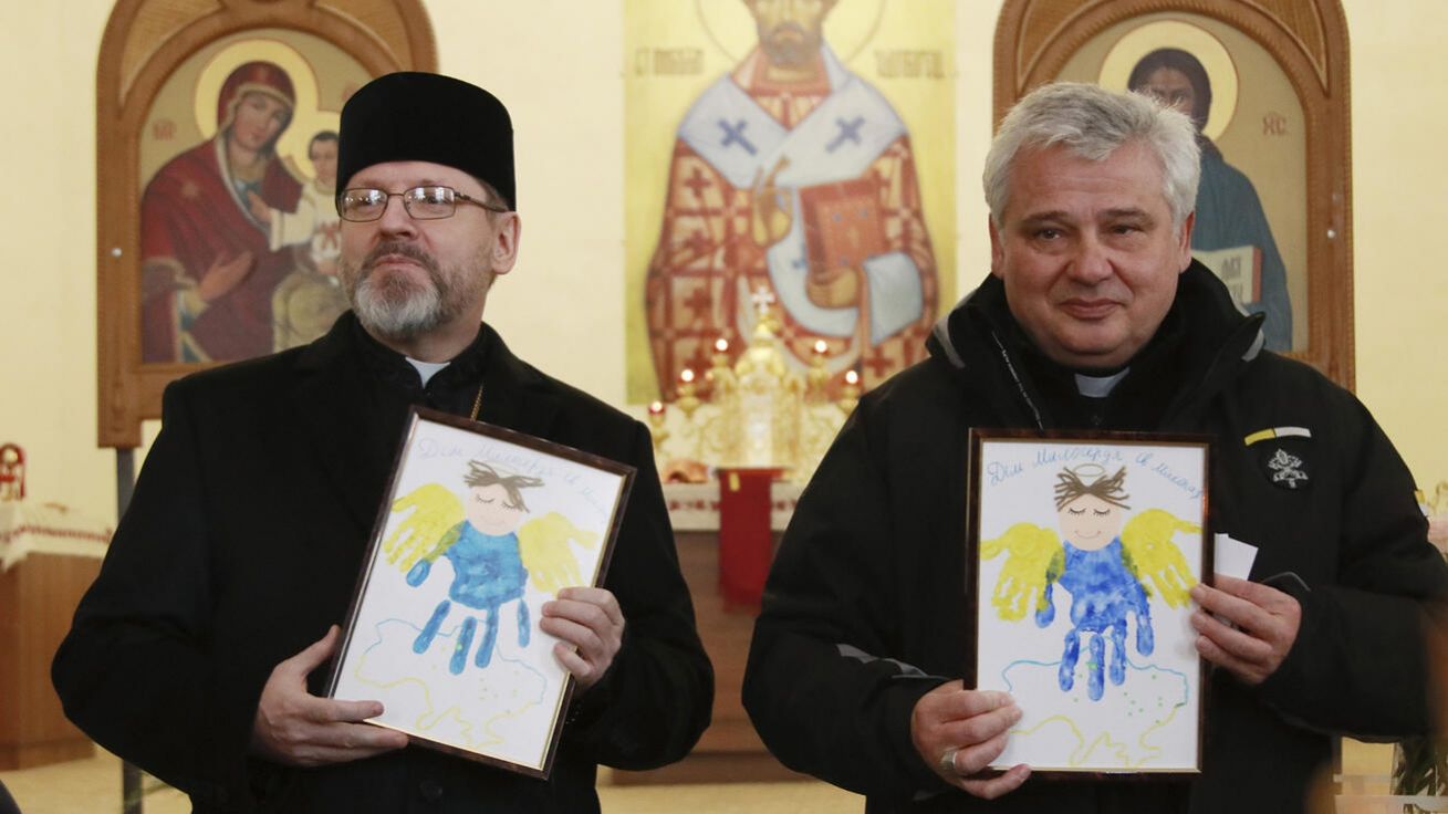 image:Image Kardinál Konrad Krajewski (vpravo) s řeckokatolickým arcibiskupem Svjatoslavem Ševčukem drží obrázky dětí při setkání s rodinami uprchlíků ve Lvově na západě Ukrajiny.