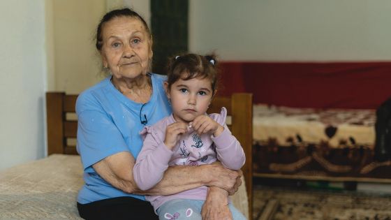 image:Image Na útěk před válkou jen v bačkorách vzpomíná jedenaosmdesátiletá paní Ljudmila s vnučkou v náručí. Už několik měsíců žije v relativním bezpečí na západě Ukrajiny. Dostat se z nejhoršího jí i její rodině vytrvale pomáhá Charita ČR. Ljudmila žila týdny ve sklepě uprostřed bojů v Zelenodolsku v Dněpropetrovské oblasti. Její dům už dnes neexistuje, zničilo ho bombardování. „Rakety padaly jako déšť,“ vzpomíná se smutkem ve dvoupokojovém bytě, kde bydlí společně se svou dcerou, zetěm, snachou a vnučkou, kteří utekli z Chersonu.