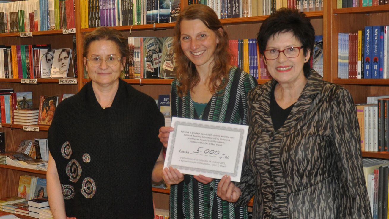image:Image Výtěžek z prodeje knihy Melodie noci bude věnován Hospici svatého Lazara v Plzni. První šek předaly autorky Romana Schuldová a Eva Hubatová sociální pracovnici hospice Ivaně Kašové (uprostřed) v Karmelitánském knihkupectví, kde je kniha také k zakoupení.