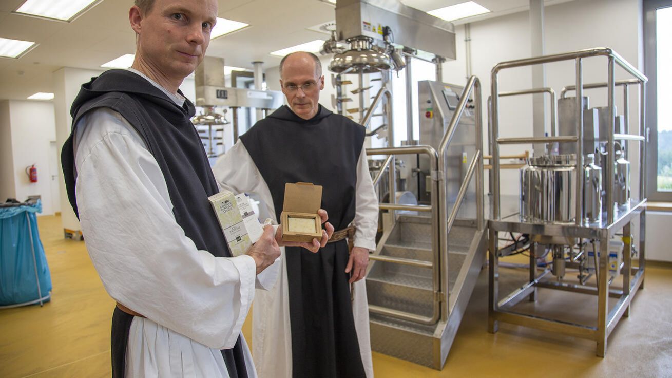 image:Image Bratr Rafael drží v ruce mýdlo a krémy, které bratři vyrábějí. Za ním stojí bratr Jiří, který má na starosti hospodaření kláštera. V pozadí je vidět zařízení, ve kterém tyto výrobky vznikají.