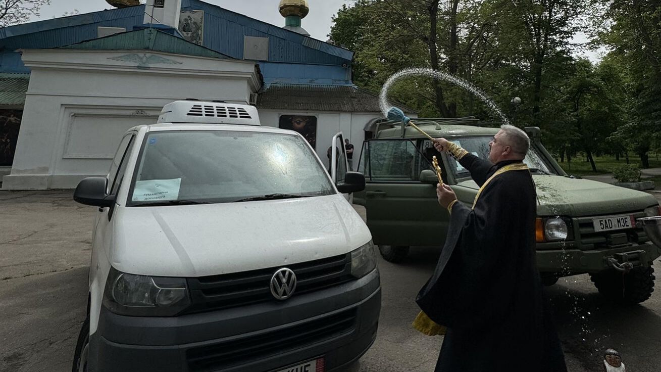 image:Image Vasyl Vyrozub žehná chladírenský vůz, který dostal od českých dárců, vedle je sanitka pořízená se sbírky Paměti národa.