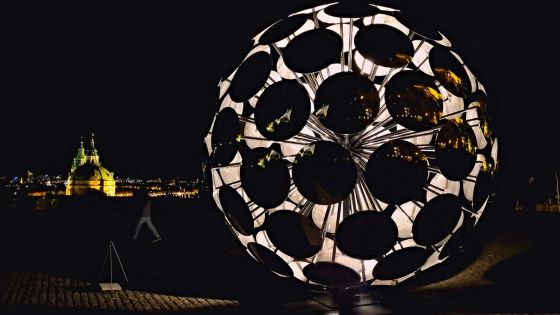 image:Image SIGNAL FESTIVAL rozzářil o víkendu v Praze i církevní stavby. Jedna z výrazných projekcí byla na Arcibiskupském paláci na Hradčanském náměstí. Byl to videomapping nazvaný Eternal Recurrence (Věčné opakování) vytvořený speciálně pro monumentální architekturu paláce. Tvůrci ho označili za digitální ságu o vzniku a vývoji forem života. Jen o pár kroků dál byla v Jižních zahradách Pražského hradu vidět kruhová instalace nazvaná ORB (na snímku, v pozadí chrám sv. Mikuláše). Vznikla již v roce 2022 jako součást velké výstavy „Forever Is Now II“, kterou pořádal Culturvator Art D’Égypte ve spolupráci s UNESCO a egyptským ministerstvem turismu a památek. Jeho první prezentace byla u pyramid v Gíze. Tvary a materiály objektu vycházejí z prvků matematiky a symboliky přítomné v klasické egyptské kultuře, a zejména právě v pyramidách. Jeho proporce odkazují na číslo „pí“ skryté v jejich geometrii.