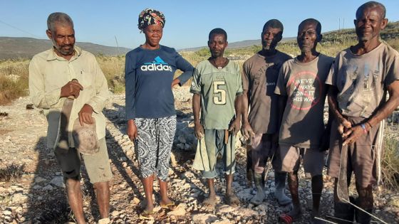 image:Image Lidé pracující na pozemku Praga-Haiti v únoru 2025. Djieuvert (úplně vpravo) má jako jediný z nich malý domek a zahrádku. Ostatní nemají žádný domov ani majetek. Spí venku nebo přespávají u známých. Zprava od Djieuverta
stojí Eliphène, Dukens, Obéir, Islène a Jeudy.