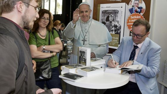 image:Image Historik Jaroslav Šebek podepisoval na stánku společnosti KatMedia svou monografii o kardinálu Tomáškovi, v pozadí portrét papeže Františka, jehož knihy byly na stánku hojně zastoupeny. O svých knižních novinkách na veletrhu besedovali také Aleš Palán či redaktorka KT Alena Scheinostová.