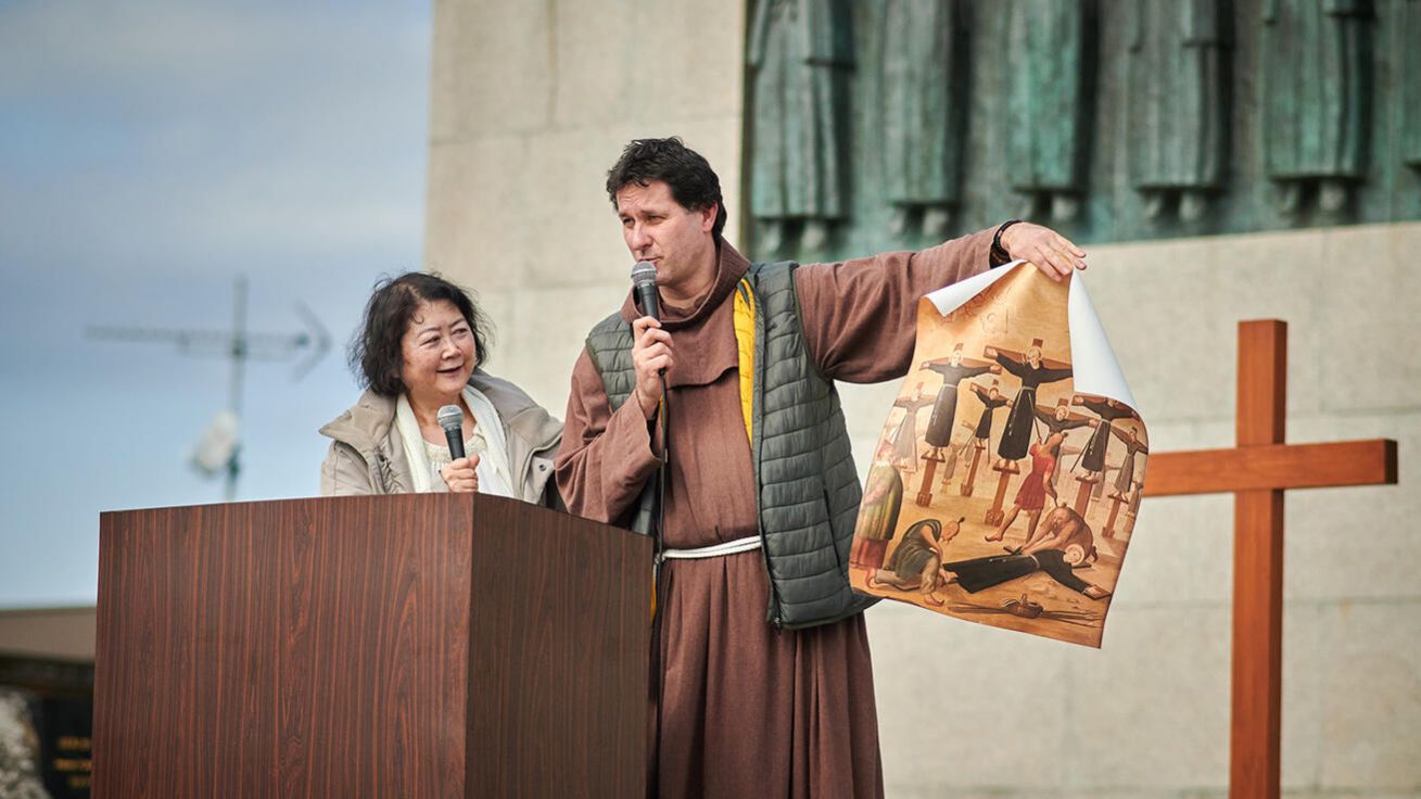 image:Image Provinciál českých františkánů Jakub Sadílek před památníkem 26 mučedníků z Nagasaki ukazuje vyobrazení jejich hromadného ukřižování v 16. století.