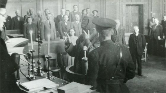 image:Image Svědkové v procesu s K. H. Frankem svědčili ještě před křížem se svíčkami. To se už brzy změnilo. Na snímku vězeň koncentračního tábora Jaroslav Hanáček. Tvář si zakrývá kvůli popáleninám utrpěným na konci války.