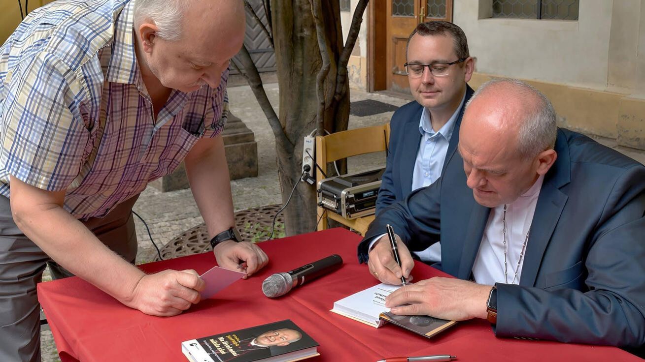 image:Image Představení knihy v Praze. Arcibiskup Josef Nuzík ji podepisuje, za ním je autor Jiří Gračka.